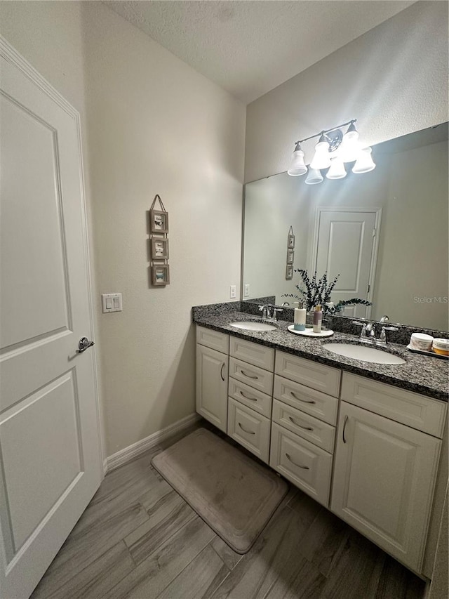14117 Larkspur Lake Dr, Winter Garden, FL 34787 - bathroom with double vanity, wood finished floors, a textured ceiling, and baseboards