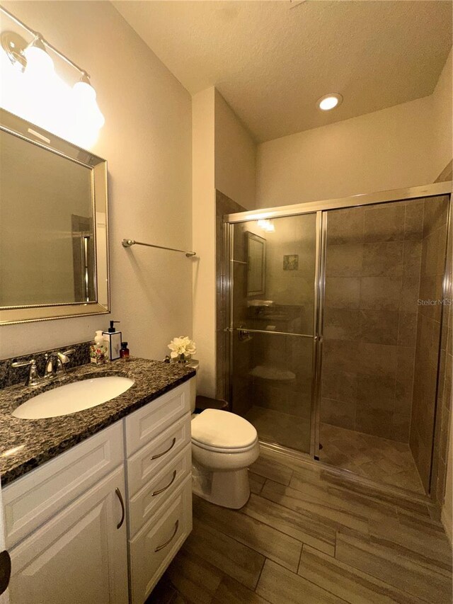 14117 Larkspur Lake Dr, Winter Garden, FL 34787 - bathroom featuring vanity, toilet, a stall shower, wood finished floors, and a textured ceiling