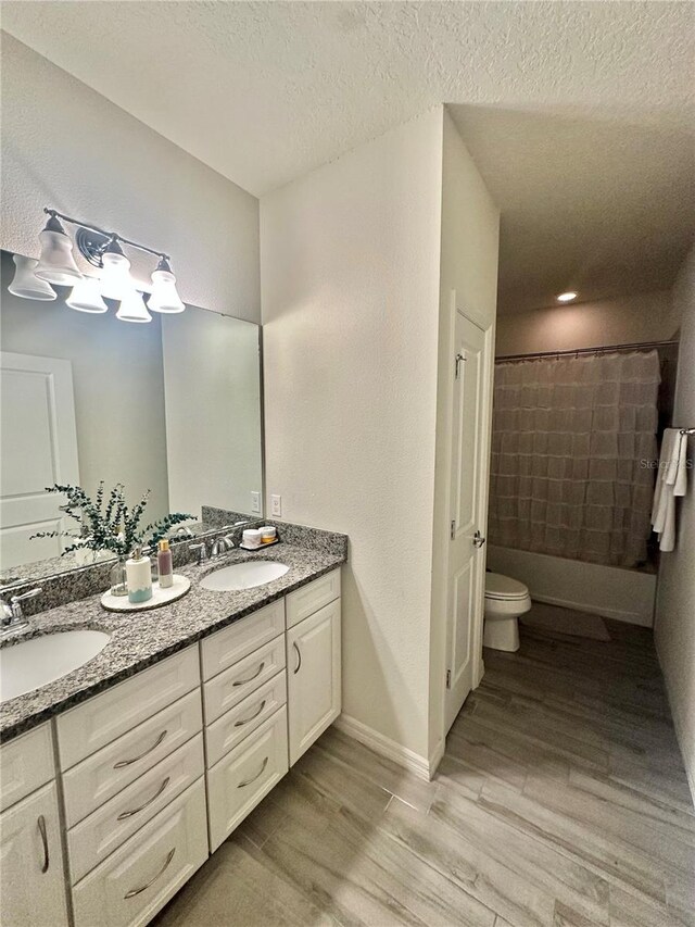 14117 Larkspur Lake Dr, Winter Garden, FL 34787 - full bathroom with double vanity, toilet, wood finished floors, a textured ceiling, and baseboards