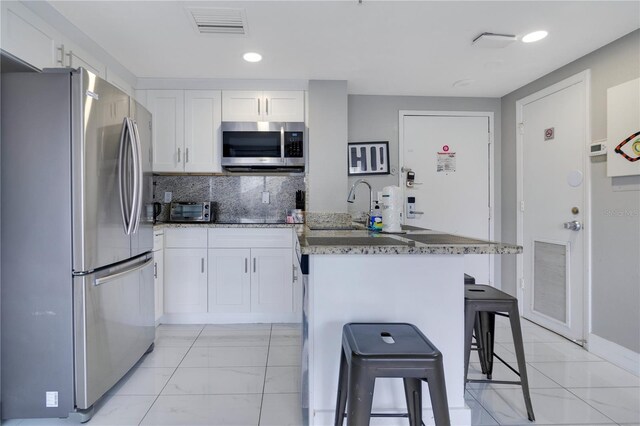 6165 Carrier Dr Unit 2605, Orlando, FL 32819 - kitchen featuring appliances with stainless steel finishes, light marble finish floors, white cabinetry, a breakfast bar, and recessed lighting
