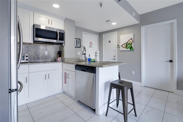 6165 Carrier Dr Unit 2605, Orlando, FL 32819 - kitchen featuring stainless steel appliances, a sink, a peninsula, white cabinets, and backsplash