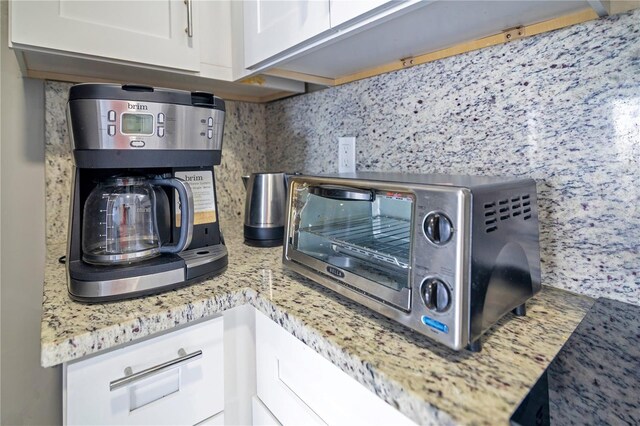 6165 Carrier Dr Unit 2605, Orlando, FL 32819 - kitchen view of decorative backsplash, white cabinets, and light stone countertops