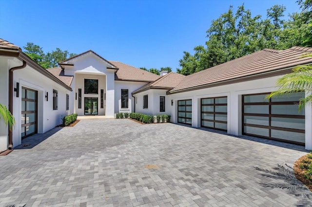 5199 Latrobe Dr, Windermere, FL 34786 - view of front of home with a tiled roof, stucco siding, decorative driveway, a garage, and french doors