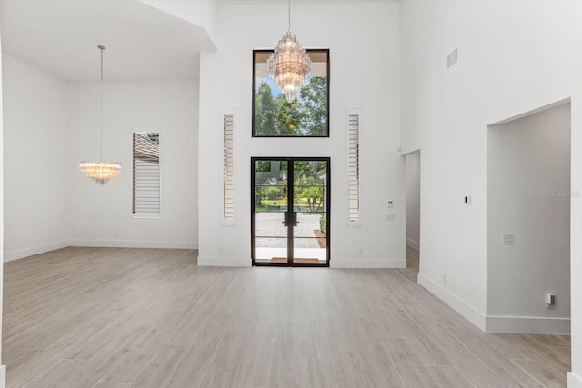 5199 Latrobe Dr, Windermere, FL 34786 - unfurnished living room with a chandelier, a towering ceiling, light wood finished floors, and baseboards