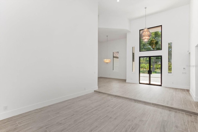 5199 Latrobe Dr, Windermere, FL 34786 - empty room featuring a towering ceiling, light wood finished floors, baseboards, and a chandelier