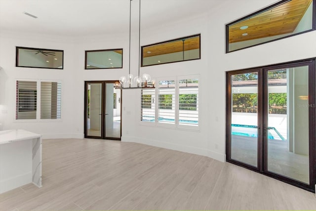 5199 Latrobe Dr, Windermere, FL 34786 - unfurnished living room featuring french doors, a towering ceiling, a chandelier, baseboards, and light wood-type flooring