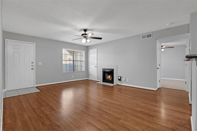 351 Lone Hill Dr Unit 206, Altamonte Springs, FL 32701 - unfurnished living room featuring a ceiling fan, a tiled fireplace, a textured ceiling, wood finished floors, and baseboards
