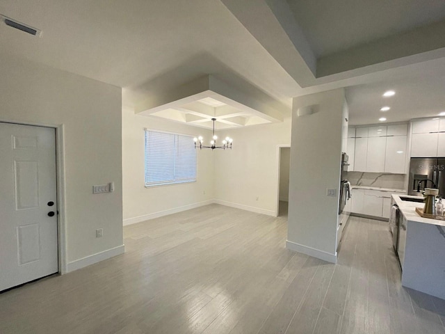 10153 Wildcat St, Port Charlotte, FL 33981 - kitchen featuring a chandelier, a sink, light countertops, light wood finished floors, and white cabinetry