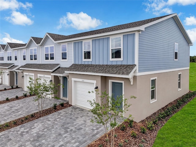 3345 Thicket St, Tavares, FL 32778 - view of property with a garage, decorative driveway, roof with shingles, board and batten siding, and stucco siding