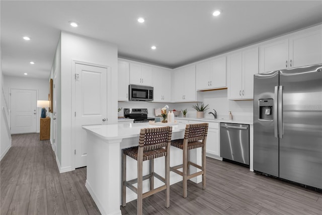 3345 Thicket St, Tavares, FL 32778 - kitchen featuring appliances with stainless steel finishes, light countertops, wood finished floors, a kitchen island, and white cabinetry