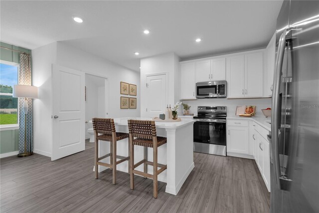 3345 Thicket St, Tavares, FL 32778 - kitchen with appliances with stainless steel finishes, a kitchen island, wood finished floors, light countertops, and recessed lighting