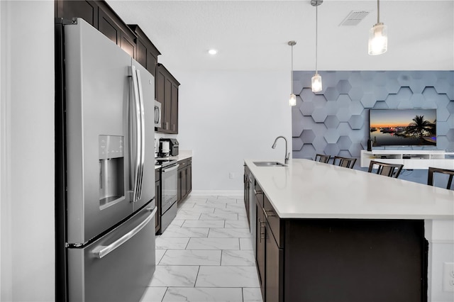 8961 Cabot Cliffs Dr, Davenport, FL 33896 - kitchen featuring appliances with stainless steel finishes, a sink, light countertops, light marble finish floors, and decorative light fixtures