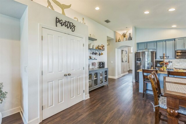 6935 Runner Oak Dr, Wesley Chapel, FL 33545 - kitchen with appliances with stainless steel finishes, arched walkways, decorative backsplash, lofted ceiling, and dark wood-type flooring