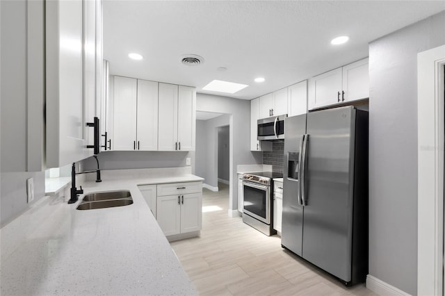 4116 SW 20th St, Ocala, FL 34474 - kitchen featuring stainless steel appliances, white cabinetry, recessed lighting, light stone counters, and a skylight