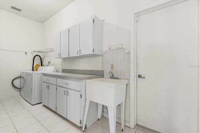 4026 S Lake Orlando Pkwy, Orlando, FL 32808 - washroom with washing machine and dryer, a textured ceiling, cabinet space, and light tile patterned flooring