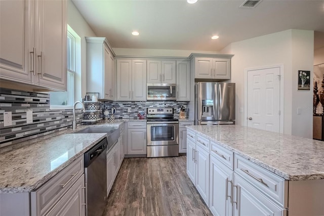 13940 Magnolia Ridge Loop, Winter Garden, FL 34787 - kitchen with appliances with stainless steel finishes, a sink, dark wood finished floors, a kitchen island, and tasteful backsplash