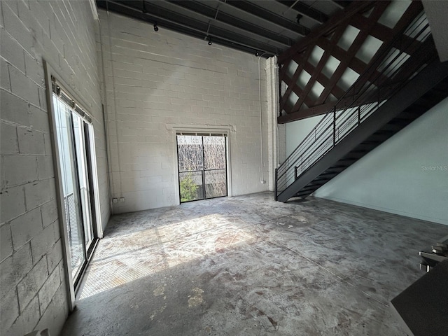 62 W Colonial Dr Unit 302, Orlando, FL 32801 - unfurnished living room with a towering ceiling, stairs, and concrete block wall