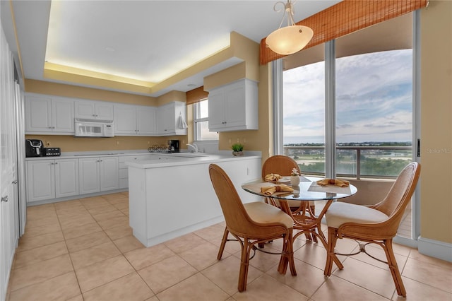 3010 Grand Bay Blvd Unit 472, Longboat Key, FL 34228 - kitchen featuring white microwave, white cabinets, light countertops, and light tile patterned floors