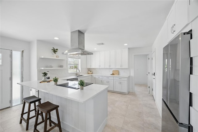 3528 Casablanca Ave, Saint Petersburg, FL 33706 - kitchen with island range hood, freestanding refrigerator, black electric cooktop, a kitchen bar, and white cabinets