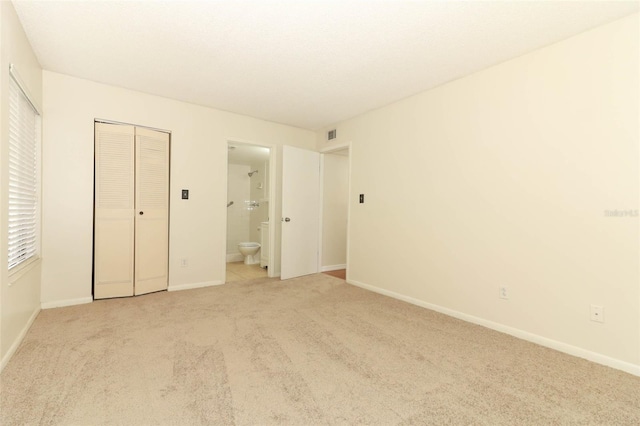1221 S Pine Ridge Cir Unit A2, Sanford, FL 32773 - unfurnished bedroom with light carpet, baseboards, a closet, and ensuite bathroom