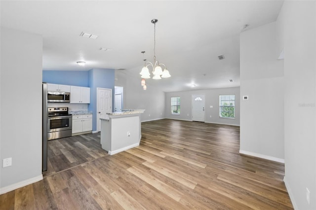 395 Alcazar Ave, De Leon Springs, FL 32130 - kitchen with appliances with stainless steel finishes, wood finished floors, white cabinetry, lofted ceiling, and open floor plan