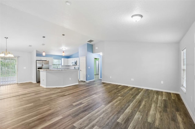 395 Alcazar Ave, De Leon Springs, FL 32130 - unfurnished living room with lofted ceiling, wood finished floors, a chandelier, baseboards, and plenty of natural light
