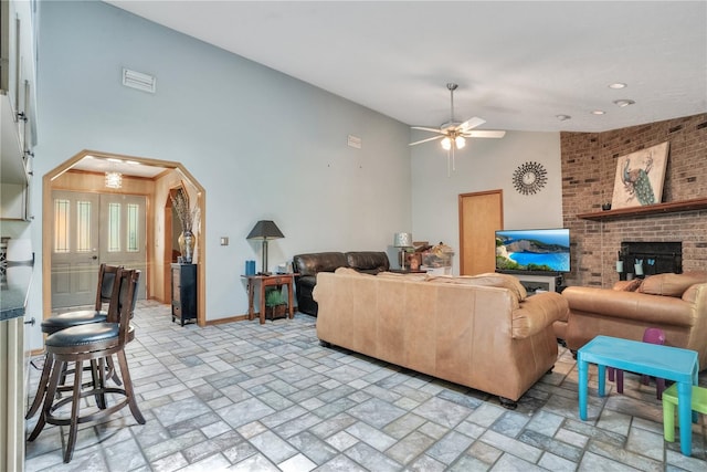 616 Magnolia St, Windermere, FL 34786 - living room featuring arched walkways, a ceiling fan, brick patterned floors, high vaulted ceiling, and a brick fireplace