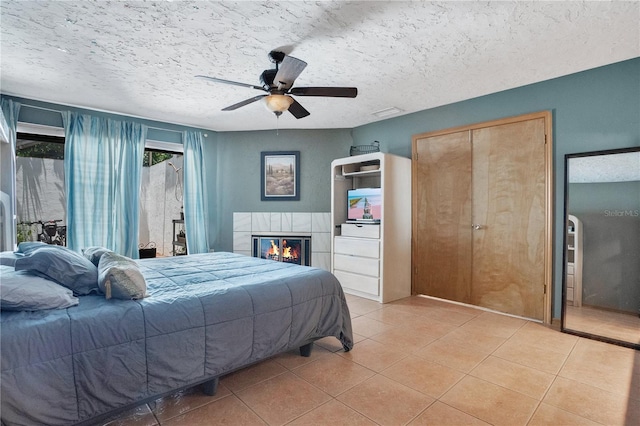 616 Magnolia St, Windermere, FL 34786 - bedroom featuring light tile patterned flooring, ceiling fan, a tiled fireplace, and a textured ceiling