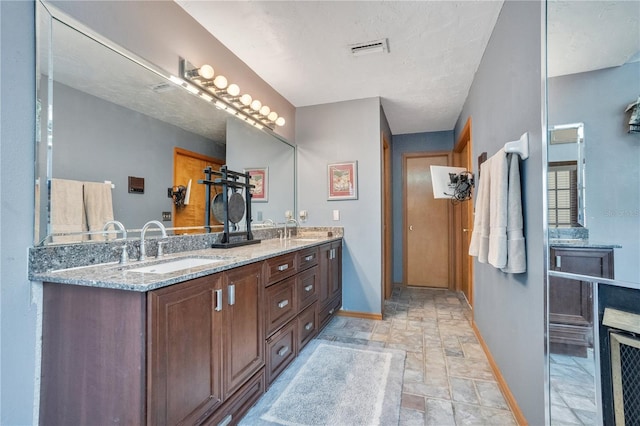 616 Magnolia St, Windermere, FL 34786 - bathroom featuring stone finish flooring and double vanity