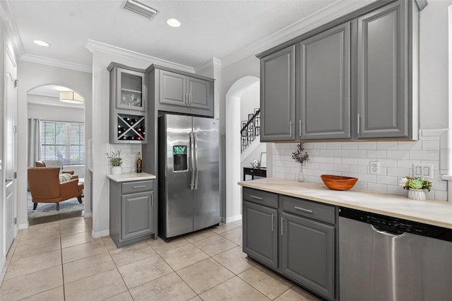 15318 Sandfield Loop, Winter Garden, FL 34787 - kitchen with appliances with stainless steel finishes, gray cabinetry, arched walkways, ornamental molding, and decorative backsplash