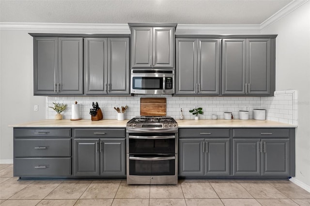 15318 Sandfield Loop, Winter Garden, FL 34787 - kitchen with stainless steel appliances, gray cabinets, tasteful backsplash, crown molding, and baseboards