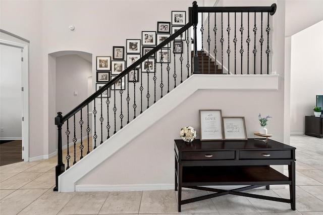 15318 Sandfield Loop, Winter Garden, FL 34787 - staircase with a towering ceiling, arched walkways, tile patterned flooring, and baseboards