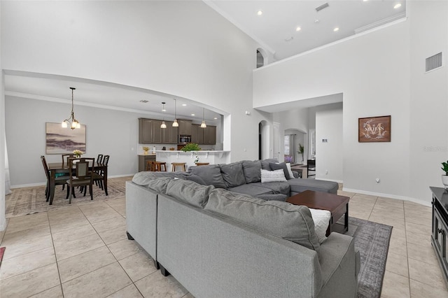 15318 Sandfield Loop, Winter Garden, FL 34787 - living room featuring arched walkways, light tile patterned flooring, a towering ceiling, baseboards, and ornamental molding