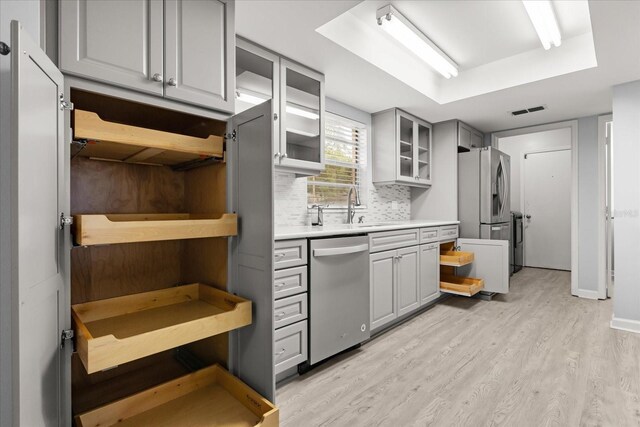 2751 Wentworth Pl, Cocoa, FL 32926 - kitchen with appliances with stainless steel finishes, gray cabinetry, light wood-type flooring, tasteful backsplash, and light countertops