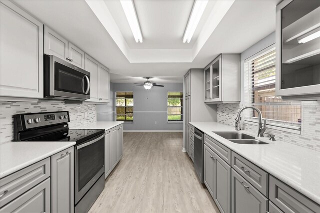 2751 Wentworth Pl, Cocoa, FL 32926 - kitchen featuring stainless steel appliances, gray cabinetry, a raised ceiling, light wood finished floors, and decorative backsplash