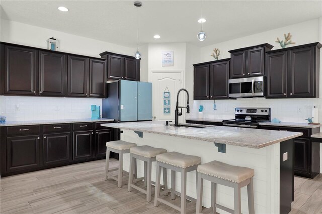 15613 Camp Dubois Cres, Winter Garden, FL 34787 - kitchen with stainless steel appliances, a sink, a kitchen bar, tasteful backsplash, and recessed lighting