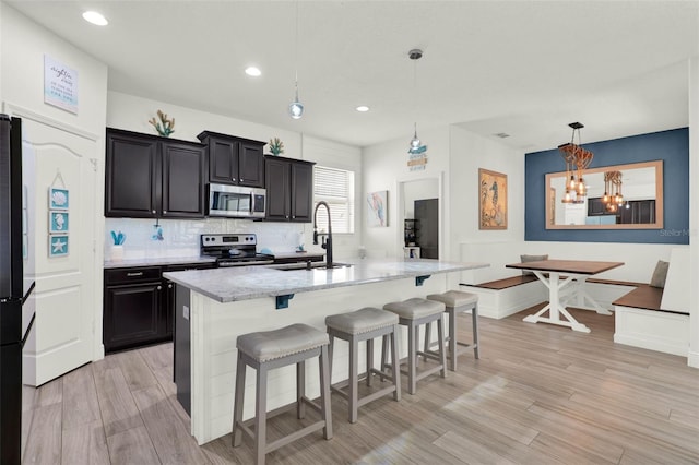 15613 Camp Dubois Cres, Winter Garden, FL 34787 - kitchen featuring appliances with stainless steel finishes, a sink, a kitchen breakfast bar, a chandelier, and light stone counters