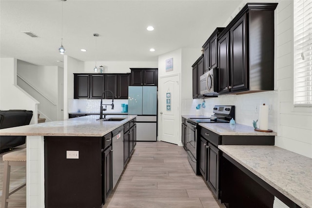 15613 Camp Dubois Cres, Winter Garden, FL 34787 - kitchen featuring appliances with stainless steel finishes, a sink, a breakfast bar, light wood finished floors, and backsplash