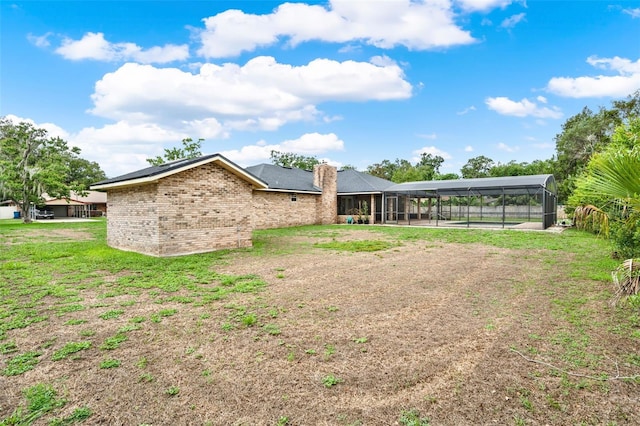 1778 Woodcrest Ln, Deland, FL 32720 - rear view of house featuring glass enclosure, a chimney, brick siding, and a lawn
