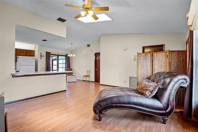 281 NE Greenbrier Ave, Port St Lucie, FL 34983 - living room with a ceiling fan, lofted ceiling, light wood-style floors, and a skylight