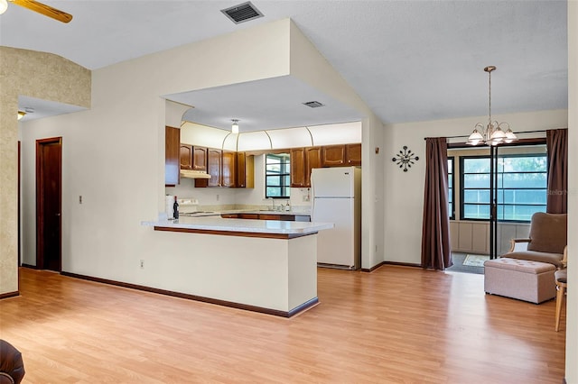 281 NE Greenbrier Ave, Port St Lucie, FL 34983 - kitchen with white appliances, light countertops, light wood-style floors, and under cabinet range hood