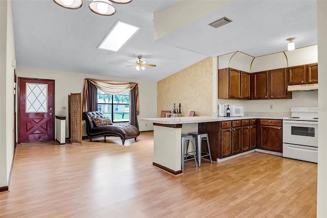 281 NE Greenbrier Ave, Port St Lucie, FL 34983 - kitchen with white appliances, open floor plan, under cabinet range hood, a skylight, and a peninsula