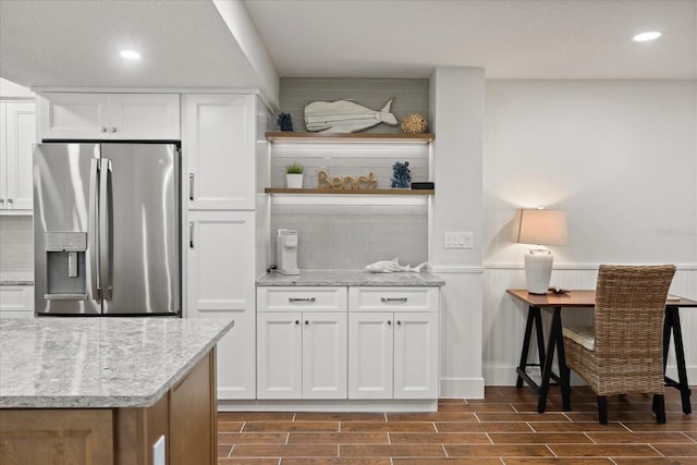 4621 S Atlantic Ave Unit 7202, Port Orange, FL 32127 - kitchen featuring stainless steel fridge, a wainscoted wall, wood finish floors, light stone counters, and white cabinets
