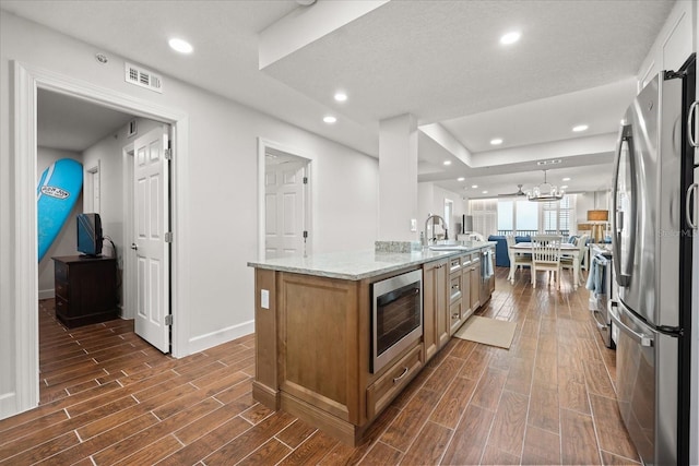 4621 S Atlantic Ave Unit 7202, Port Orange, FL 32127 - kitchen featuring appliances with stainless steel finishes, dark wood finished floors, brown cabinetry, light stone countertops, and a sink