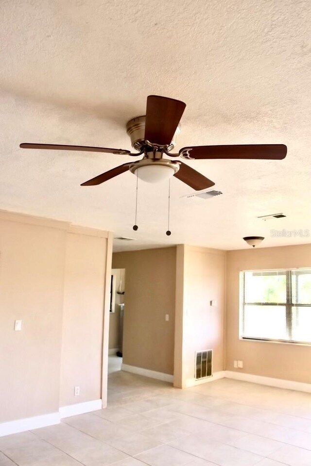 425 Walnut St, Daytona Beach, FL 32114 - spare room featuring a ceiling fan, light tile patterned floors, a textured ceiling, and baseboards