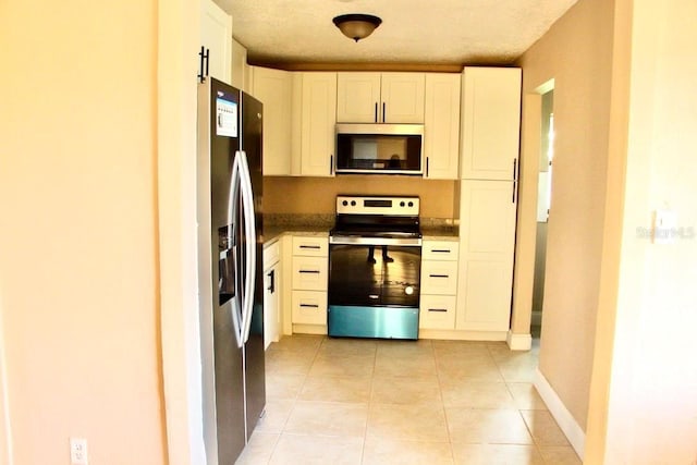 425 Walnut St, Daytona Beach, FL 32114 - kitchen featuring stainless steel appliances, white cabinets, light tile patterned floors, and baseboards