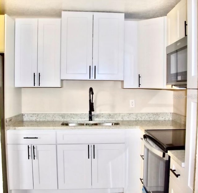 425 Walnut St, Daytona Beach, FL 32114 - kitchen featuring a sink, stainless steel appliances, white cabinets, and light stone countertops
