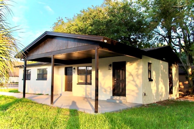 425 Walnut St, Daytona Beach, FL 32114 - back of house with a patio, stucco siding, and a lawn