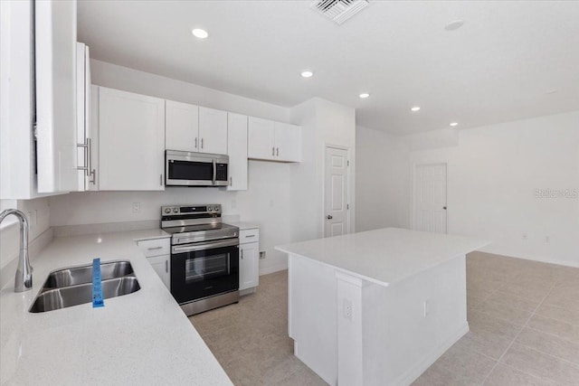 1267 Stockwell Ave, Saint Cloud, FL 34771 - kitchen with stainless steel appliances, white cabinetry, recessed lighting, light countertops, and a kitchen island