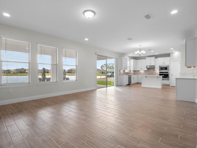 11027 Hollow Bay Dr, Winter Garden, FL 34787 - unfurnished living room featuring a chandelier, baseboards, recessed lighting, and light wood finished floors